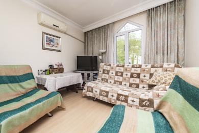 Proprietate în Alanya, living cu canapea cu model, podele din lemn deschis, lumină naturală de la o fereastră mare și atmosferă confortabilă.