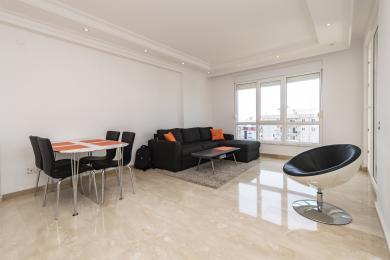 Lichte Alanya appartement woonkamer met marmeren vloeren, moderne meubels en natuurlijk licht van grote ramen.