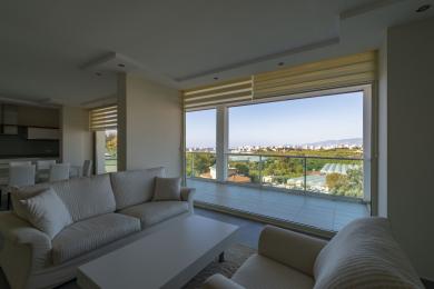 Oq divanlar, balkon va panoramali shahar manzaralari bilan yorug' Alanya yashash xonasi.