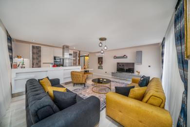 Alanya mulki: Ochiq oshxonasi, zamonaviy divanlari va qulay muhit yaratuvchi zamonaviy yoritgichlari bo'lgan yorug', zamonaviy yashash xonasi.