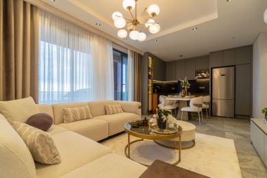 Alanya woning: Lichte, open woonkamer met moderne keuken, neutrale tinten en stijlvolle globe kroonluchter.