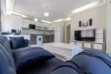 Alanya Apartment Wohnzimmer mit moderner Küche, plüschigem blauem Sofa und heller, einladender Atmosphäre.