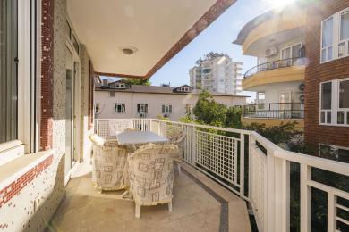 Mozaika divarları, daş döşəməsi və açıq havada yemək dəsti ilə rahat bir atmosfer yaradan günəşli Alanya balkonu.