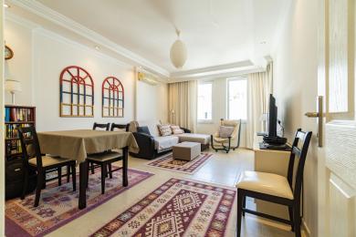 Yorug' Alanya kvartirasining kafel pollari, qulay o'rindiqlari, ovqatlanish joyi va dekorativ deraza san'ati bilan jihozlangan yashash xonasi.