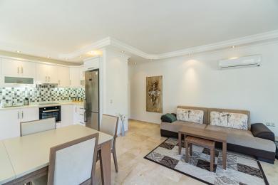 Lys Alanya leilighet stue med et moderne kjøkken, spisebord, komfortabel sofa og marmorgulv.