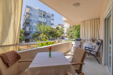 Alanya balkonida stol, stullar va quyoshli binolar manzarasi.
