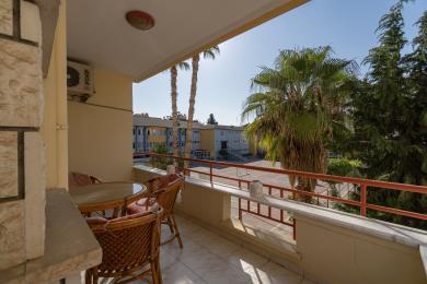 Zonnig Alanya balkon met rotan meubilair biedt een ontspannende buitenruimte en uitzicht op weelderig groen.
