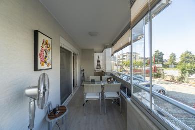 Balkon nekretnine u Alanji sa staklenim kućištem, podom od pločica, trpezarijskim setom i svetlom, prozračnom atmosferom.