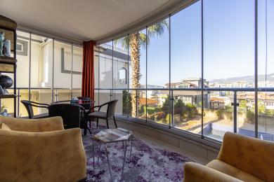 Яркі, закрыты балкон у Аланіі мае шкляныя сцены, зручныя сядзенні і панарамны від на горад.