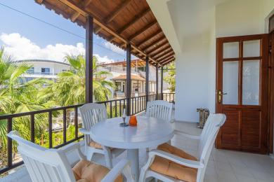 بالکن ملک در آلانیا با سقف چوبی، مبلمان پلاستیکی سفید و فضای روشن و مطبوع با چشم انداز فضای سبز سرسبز.