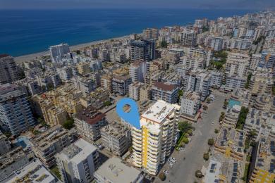 منظر جوي لعقار في ألانيا يظهر موقع المبنى بالقرب من الشاطئ ومركز المدينة.