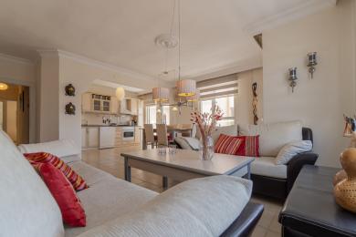 Alanya ingatlan: Világos, nyitott terű nappali modern konyhával, csempepadlóval, kényelmes ülőhelyekkel és meleg, hívogató légkörrel.