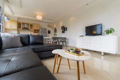 Alanya eiendom stue med en svart skinnsofa, åpen kjøkkenløsning og lys, moderne innredning.