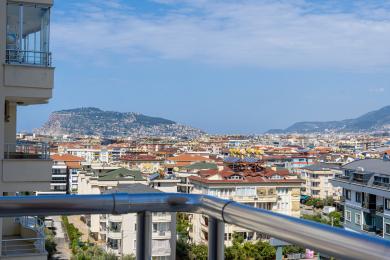 Alanya shahri va tog' manzarali balkon, yorug' quyoshli muhit.
