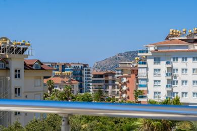 A balcony view of Alanya apartments under sunny skies with lush greenery.