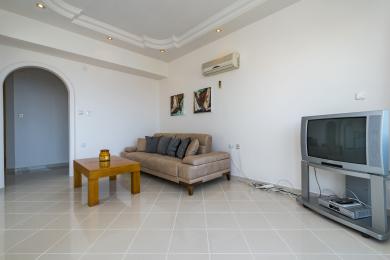 Yorug' kvartiraning yashash xonasida qulay divan, zamonaviy san'at asarlari va boshqa xonaga olib boruvchi ravoqli eshik mavjud.