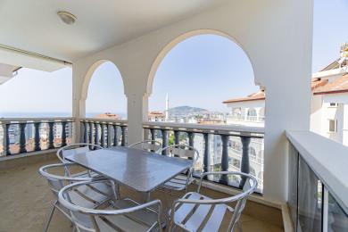 Balkon nekretnine u Alanji sa lučnim otvorima, pogledom na grad i metalnim stolom i stolicama pri jakoj dnevnoj svjetlosti.
