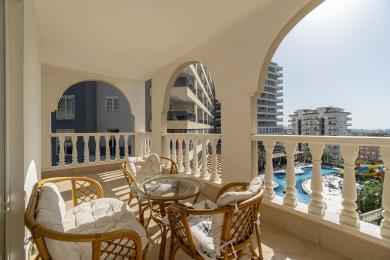 Alanya mulkidagi rattan mebellari, marmar pollari va hovuzga qaragan yorqin quyosh nurlari tushadigan balkon.