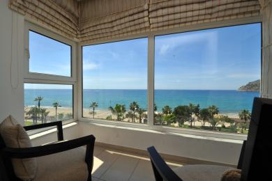 Alanya mulkidagi balkon, kafel qoplamali, qulay stullar va katta derazalar orqali ajoyib okean manzarasi.