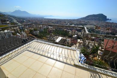 Alanya mulkidagi kafel qoplamali balkon, nafis temir panjara va shahar va qirg'oqning panoramik manzaralari.