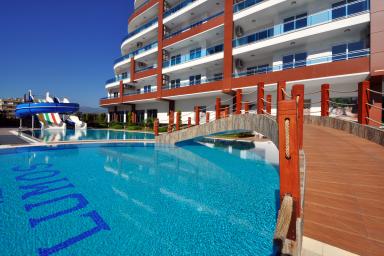 Luxuriöses Alanya-Ferienhaus mit Pool, Wasserrutsche und Brücke, das eine entspannende Urlaubsatmosphäre bietet.