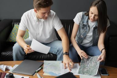 Un cuplu planifică o vacanță în Alanya, analizând hărți și documente în apartamentul lor închiriat, atmosferă relaxată.